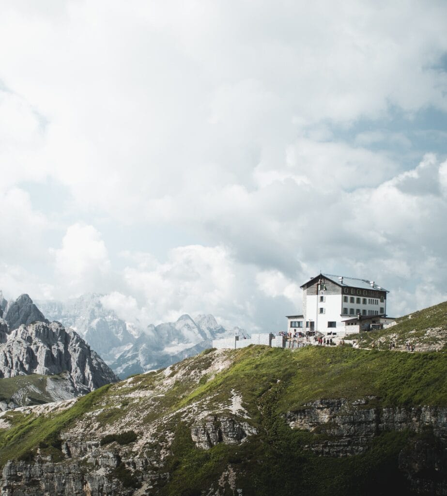 Landscape view of mountain refuge in the Dolomites with cloudy sky and green grass