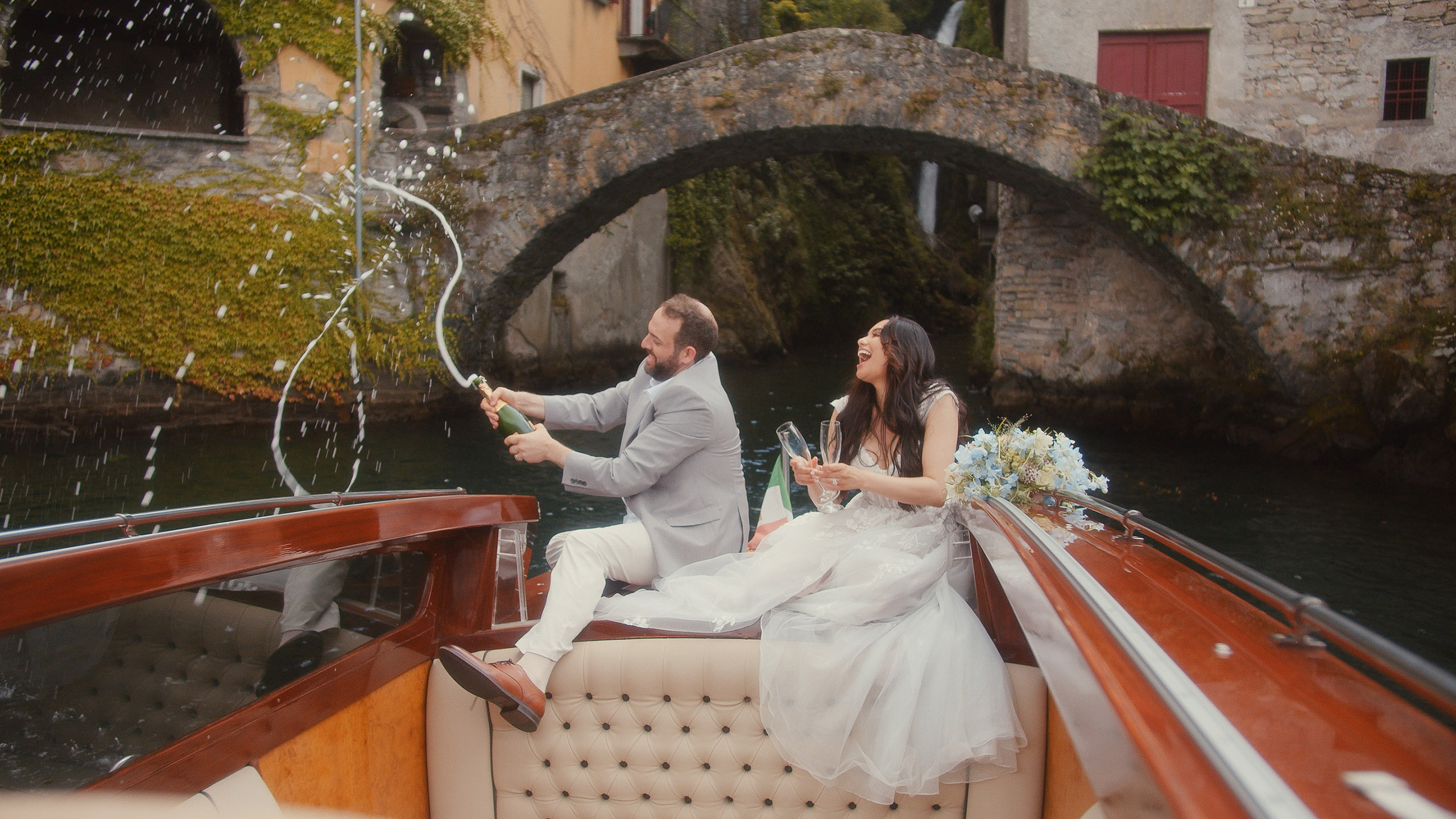 Lake Como Elopement - Bride and groom popping champagne from the boat at Lake Como in Italy
