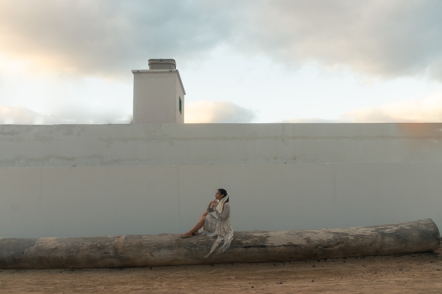 Bride sitting on a bench in front of a white building in La Graciosa during wedding photoshoot in La Graciosa